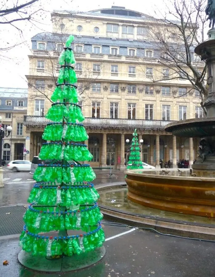 Christmas Tree made from recycled green bottles beside a fountain in Paris, another recycled bottle tree is in the background